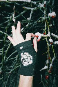 Midsection of woman with hand on plant during winter