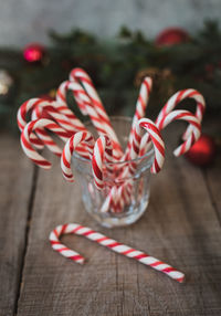 Close up of a cup full of candy canes against christmas backdrop.