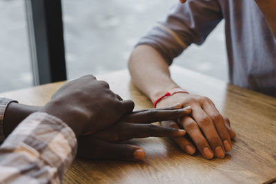 Man touching friend's hand at table in cafe