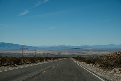 Road by landscape against blue sky