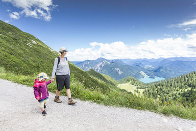 Mother with daughter on mountain against sky