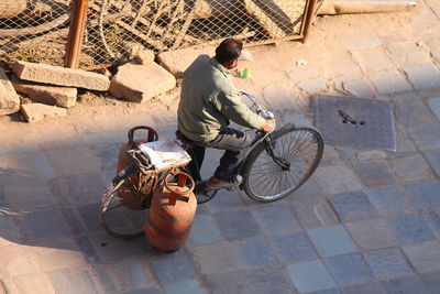 High angle view of man carrying gas cylinders on bicycle