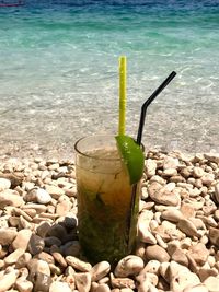 Close-up of drink on pebbles at beach