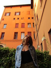 Low angle view of young woman standing against building in city