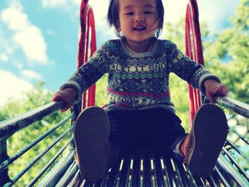 Low angle portrait of cute girl sliding in playground