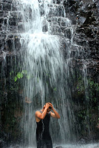 Man standing by waterfall in forest