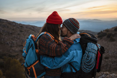 Midsection of women on mountain against sky during sunset