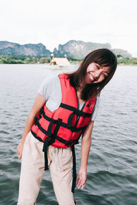 Portrait of smiling woman standing against lake