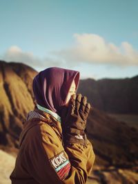 Midsection of person wearing hat on land against sky