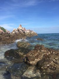 Rocks in sea against blue sky