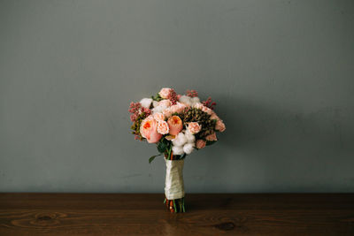 Close-up of flower vase on table against wall