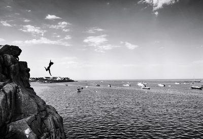 Silhouette woman diving into sea against sky