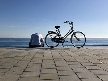 Man riding bicycle by sea against sky