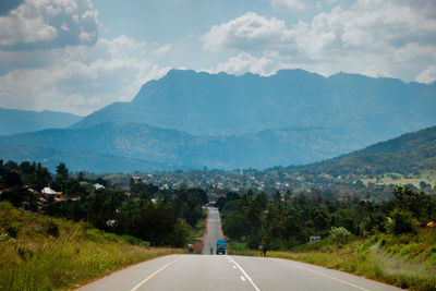Road leading towards mountains against sky