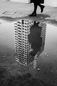 Low section of person standing on puddle at beach