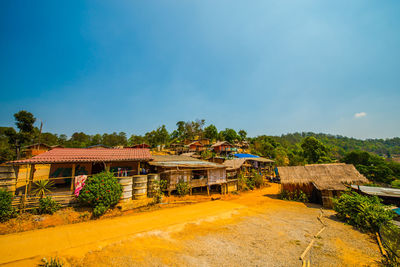 Houses by trees against blue sky