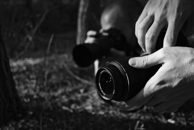 Cropped hands holding camera over grassy field