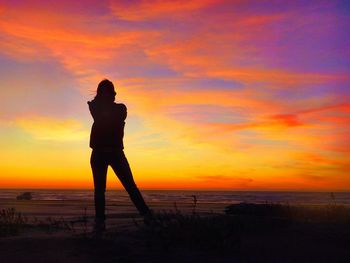 Silhouette man standing on beach against sky during sunset