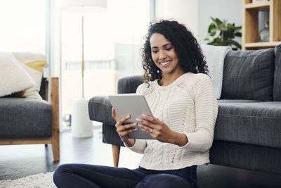 Young woman using mobile phone while sitting on sofa