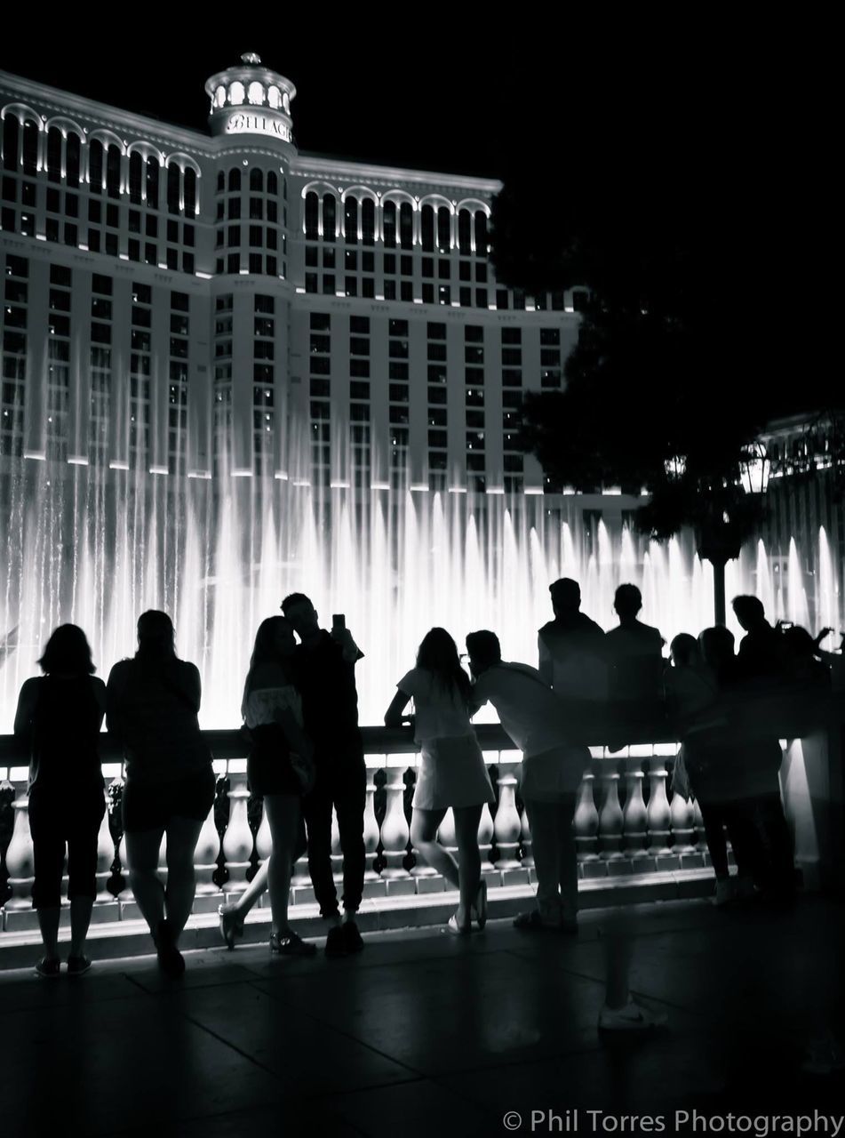 SILHOUETTE OF PEOPLE IN FOUNTAIN AT NIGHT