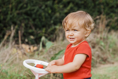 Close-up of girl holding steering wheel against plants