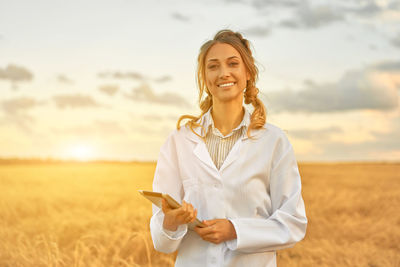 Portrait of smiling young woman standing on field