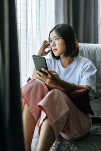 Young woman using mobile phone at home