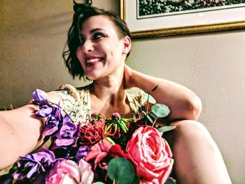 Portrait of smiling woman sitting by potted plant