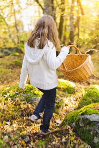 Girl walking through autumn forest, picking mushrooms