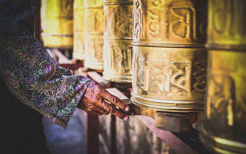 Cropped hand by prayer wheel at buddha temple