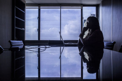 Reflection of woman sitting on glass window