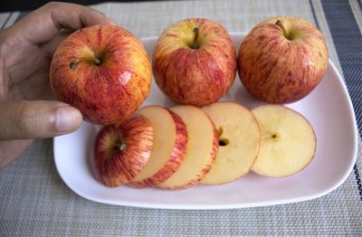 High angle view of hand holding apple on table