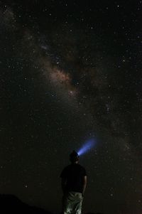 Rear view of man standing against star field at night