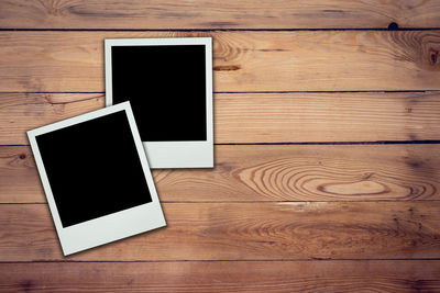 High angle view of blank photographs on wooden table