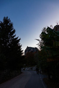 Empty road amidst trees against sky in city