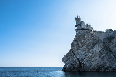 Rock formation in sea against blue sky