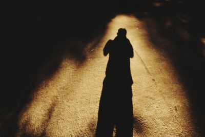 Shadow of man on illuminated street light at night
