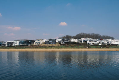 Buildings by lake against sky in city