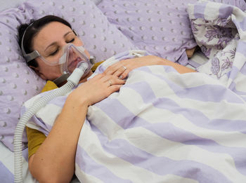Woman wearing oxygen while sleeping on bed in hospital