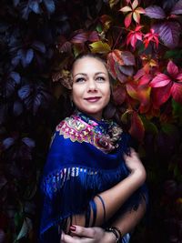 Smiling mid adult woman looking away while standing by plants at night