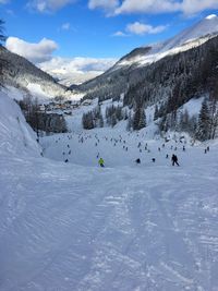 People skiing on snowcapped mountain against sky