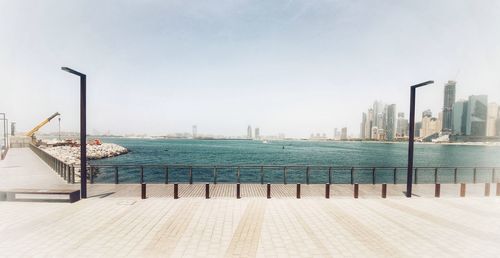 Pier by sea against buildings in city against clear sky