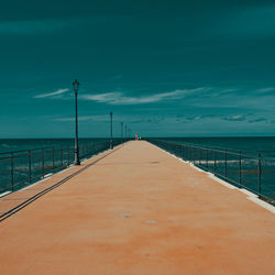 Surface level of pier leading to calm blue sea