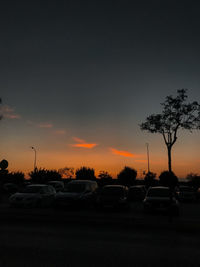 Cars on street against sky at sunset