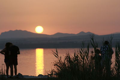 Silhouette of person standing on lakeshore