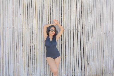 Woman in swimsuit standing by bamboos