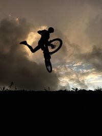 Low angle view of silhouette man jumping against sky during sunset