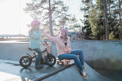 Mom helping her daughter with her helmet in a skatepark