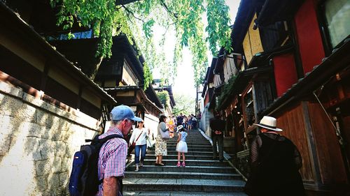 Rear view of people walking on staircase amidst buildings