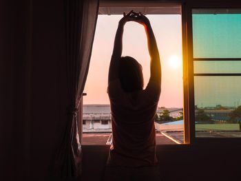 Rear view of silhouette woman standing against window